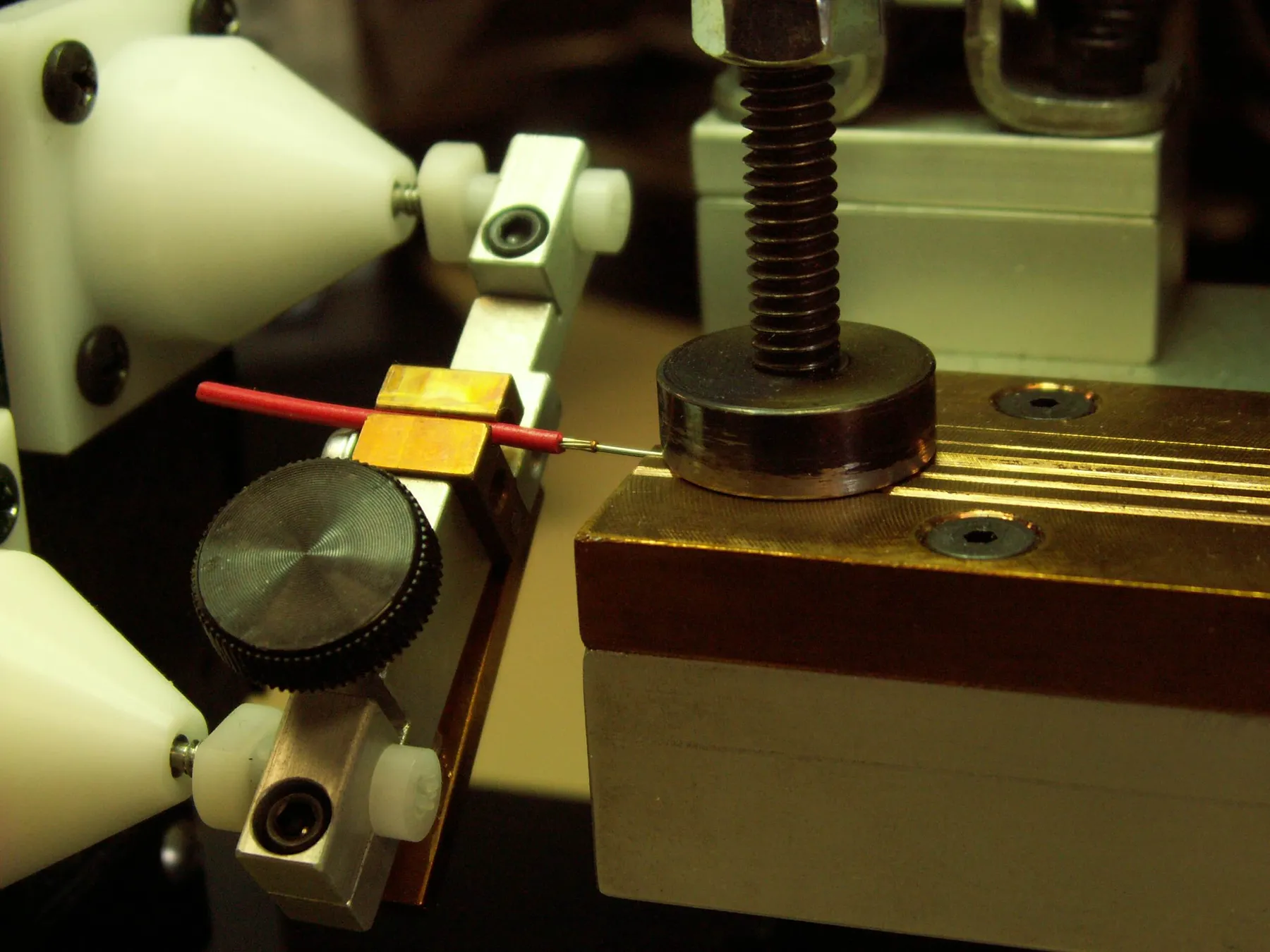 Fine wire positioned between white electrode cones on the bench fixture, close view