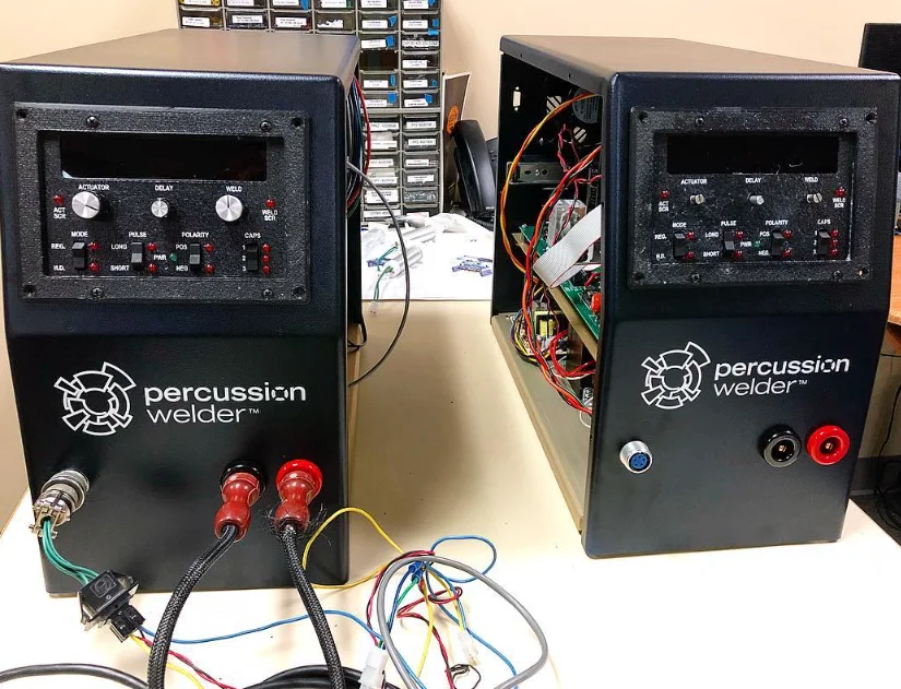 Two Percussion Welder 858 units side by side, the one on the right with its side open to show the wiring and circuit board
