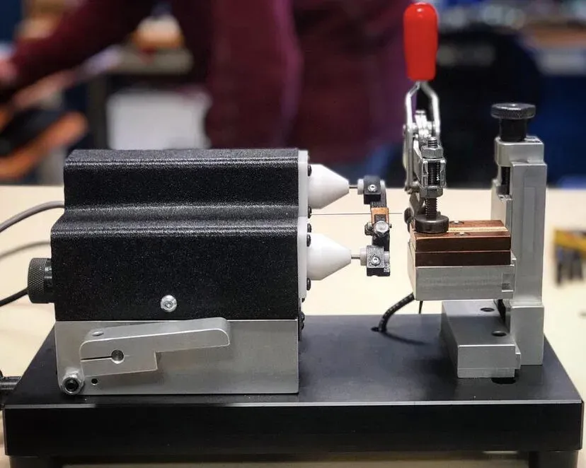 Bench fixture with electrode cones and red toggle clamp on a workbench