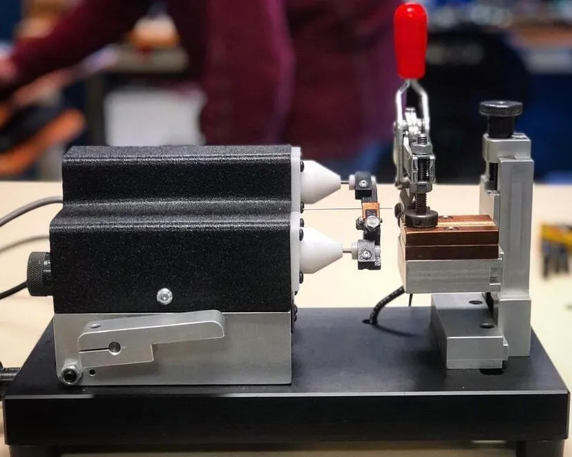 Bench fixture with electrode cones and red toggle clamp, side view