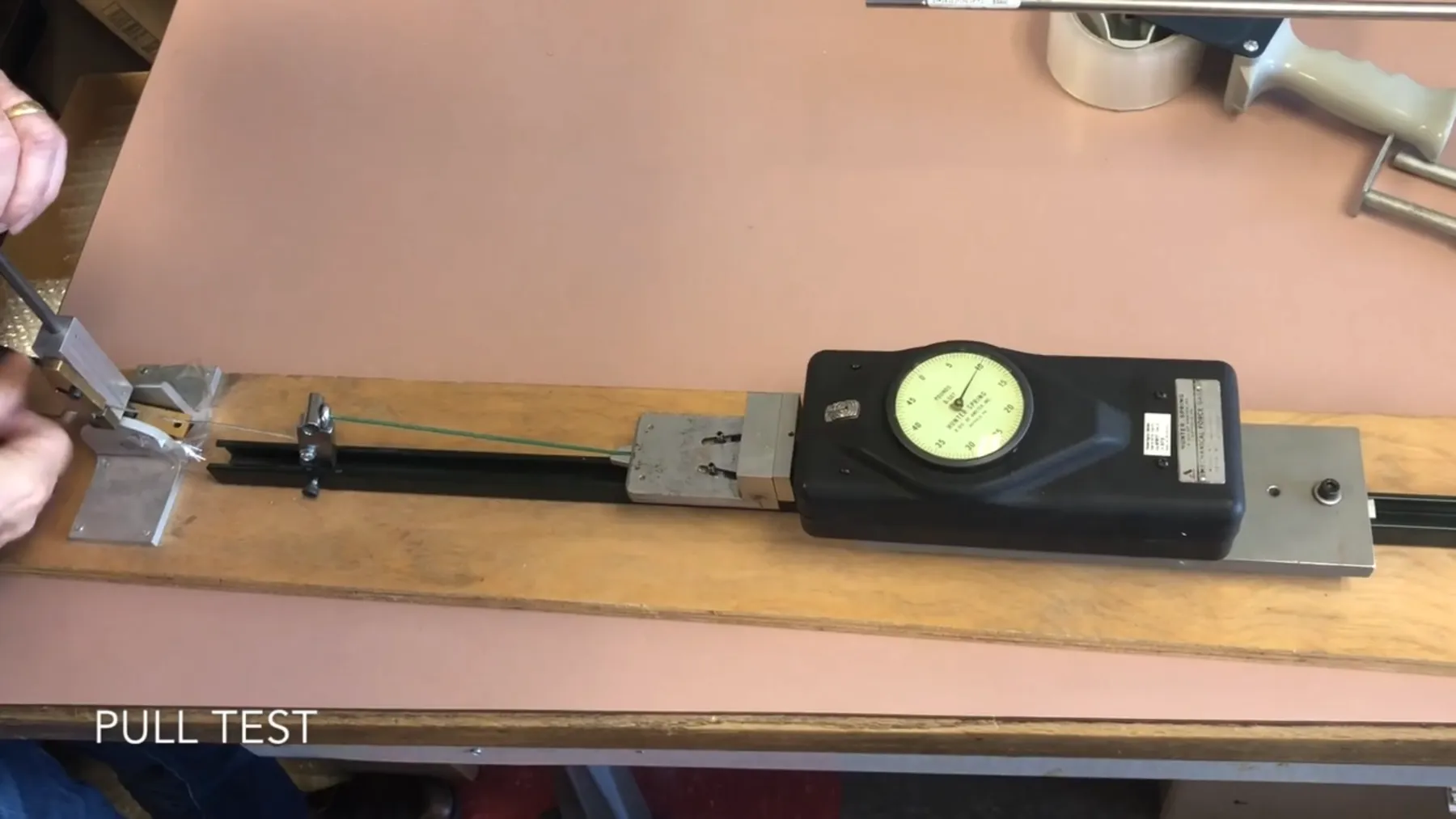 Pull test setup with a dial gauge on a rail, captioned Pull Test