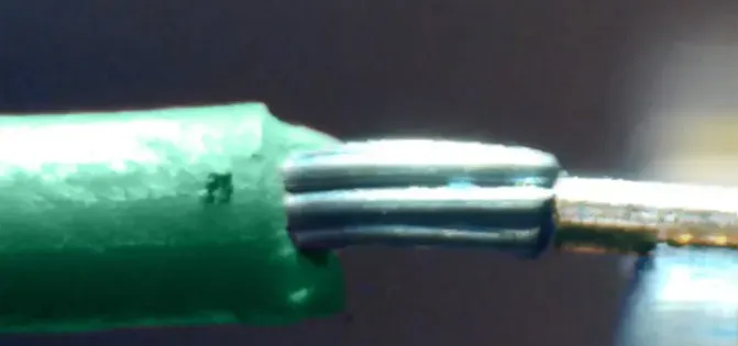 Magnified view of a green insulated wire joined to a metal tip