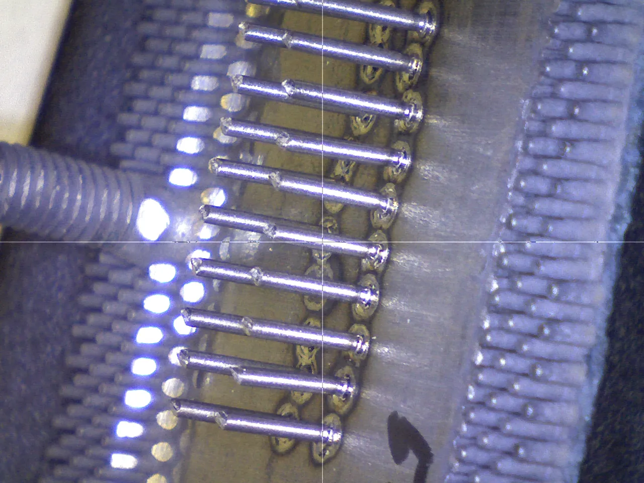 Magnified row of pins on a connector lit by bright light