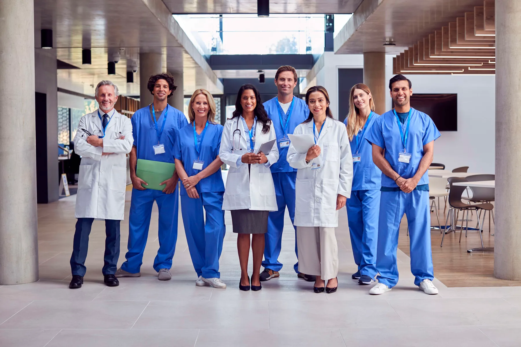 Portrait Of Multi-Cultural Medical Team Wearing Uniform Standing Inside Hospital Building